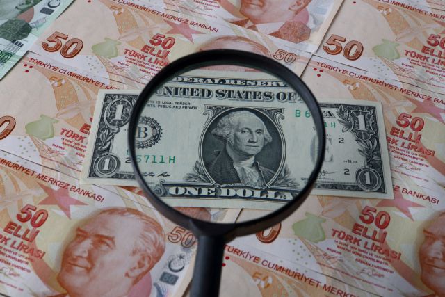 FILE PHOTO: A U.S. one dollar banknote is seen through a magnifying lens on top of Turkish lira banknotes in this illustration